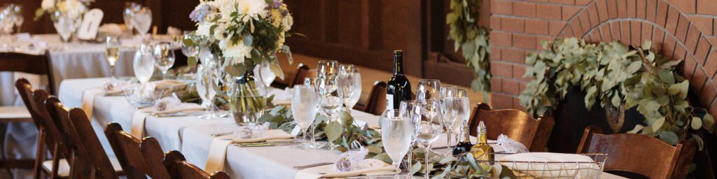 An interior view of long tables set-up for a wedding reception with pretty flowers in vases