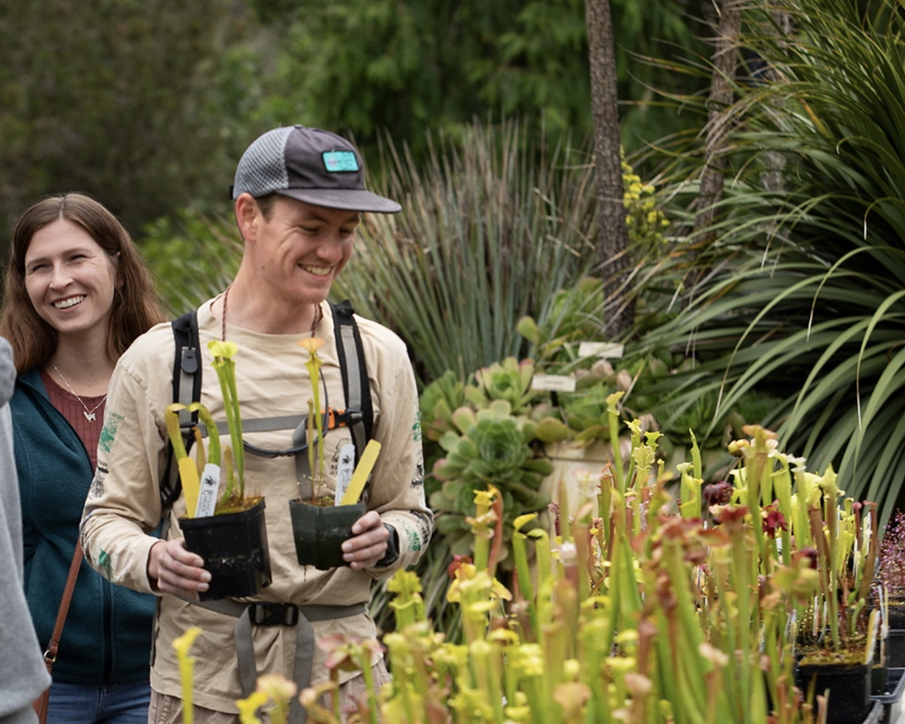 People smiling while holding interesting plants in the Garden