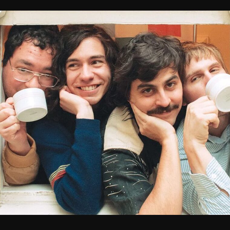 Four smiling men sitting close together