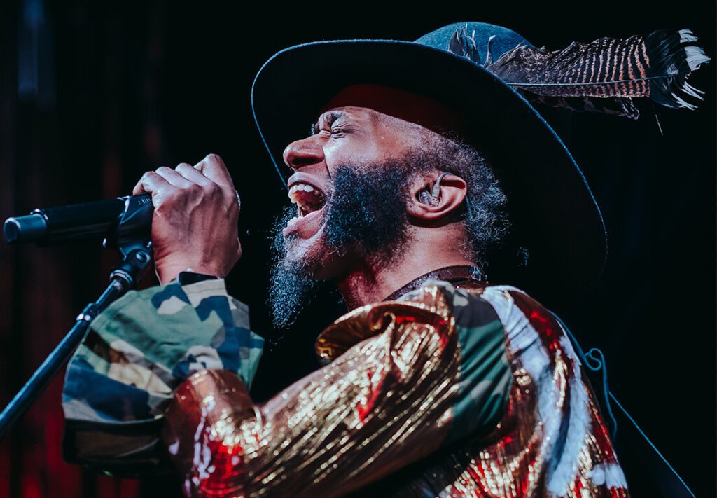 Musician Fantastic Negrito singing into microphone.