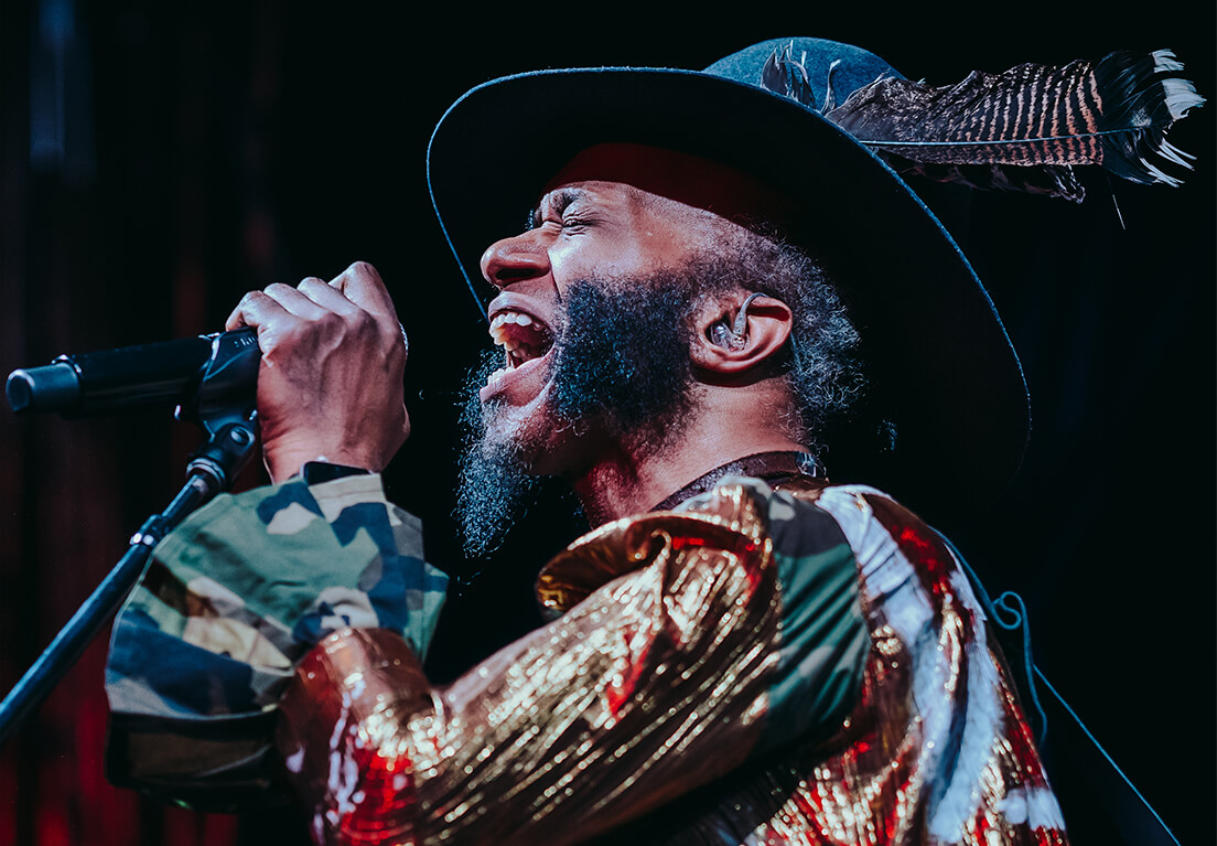 Musician Fantastic Negrito singing into microphone.