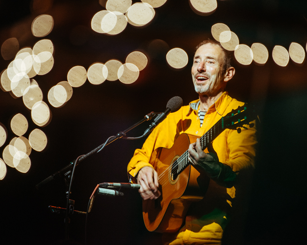 Jonathan Richman playing guitar and singing at microphone
