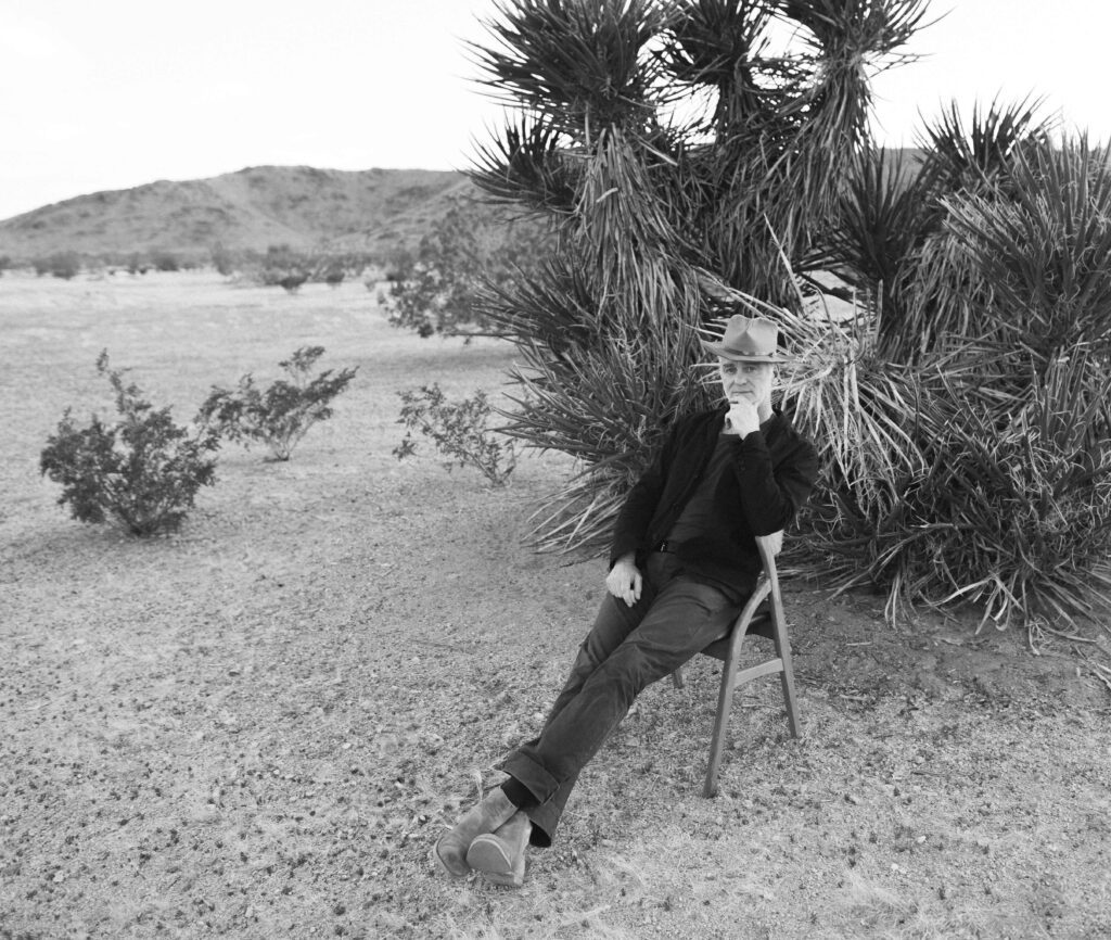 Musician Sean Hayes seated with desert plants.