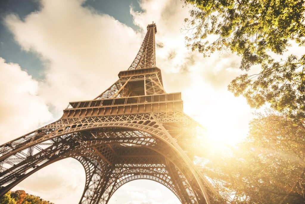 Photo of the Eiffel Tower looking up with sunlight and trees