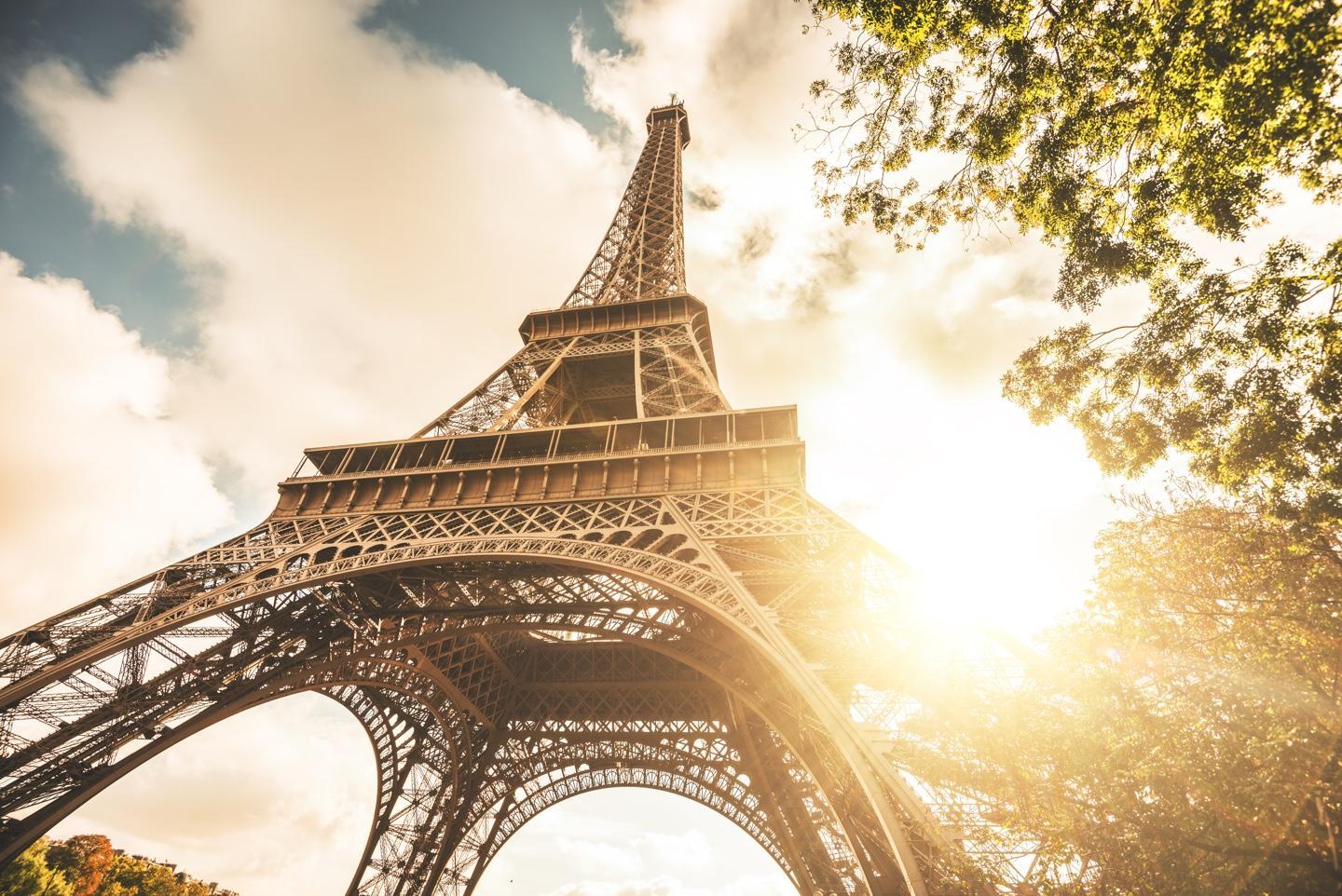 Photo of the Eiffel Tower looking up with sunlight and trees